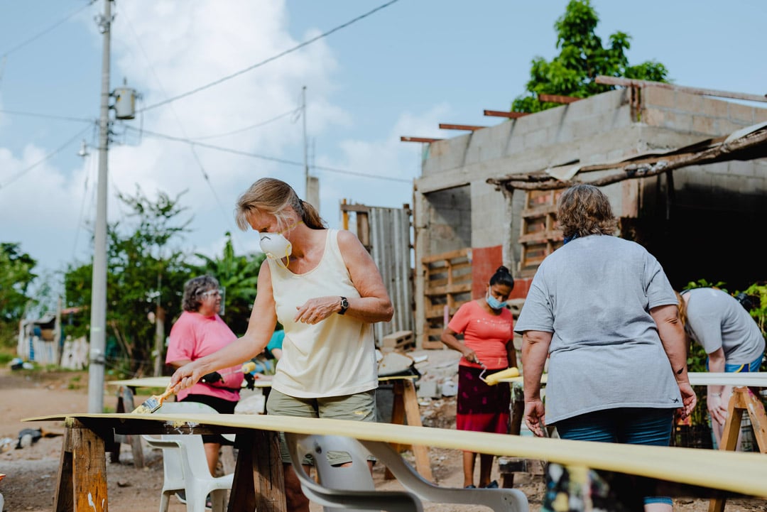 Una mujer voluntaria pinta el siding de una casa de esperanza con JUCUM Mazatlán